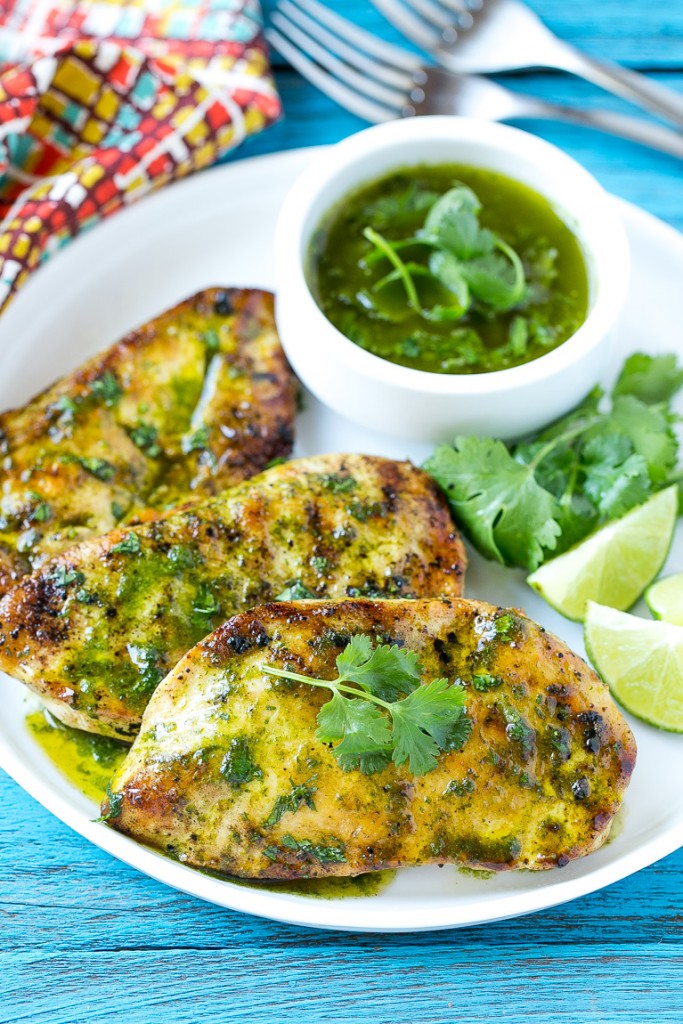 Una fuente de pechugas de pollo con cilantro y lima adornadas con hojas frescas de cilantro y rodajas de lima.