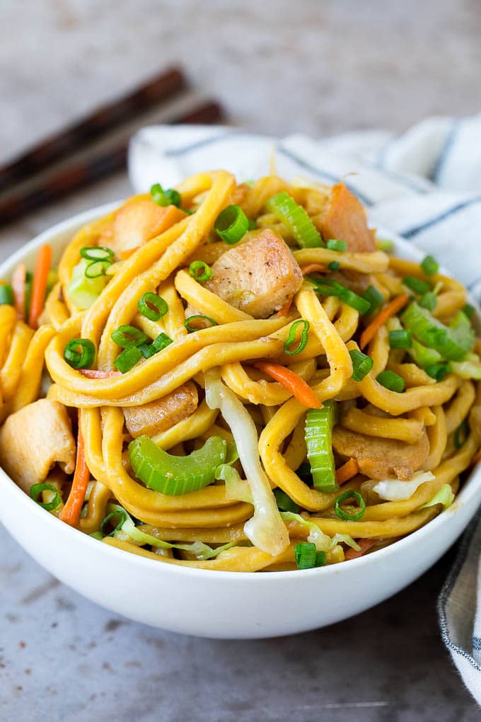 Un plato de pollo lo mein con fideos y verduras.