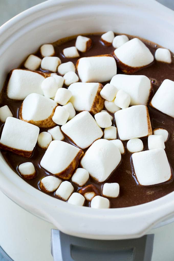 Chocolate caliente en olla de cocción lenta cubierto con una variedad de malvaviscos.