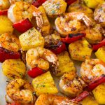 Brochetas de gambas y piña, adornadas con perejil.