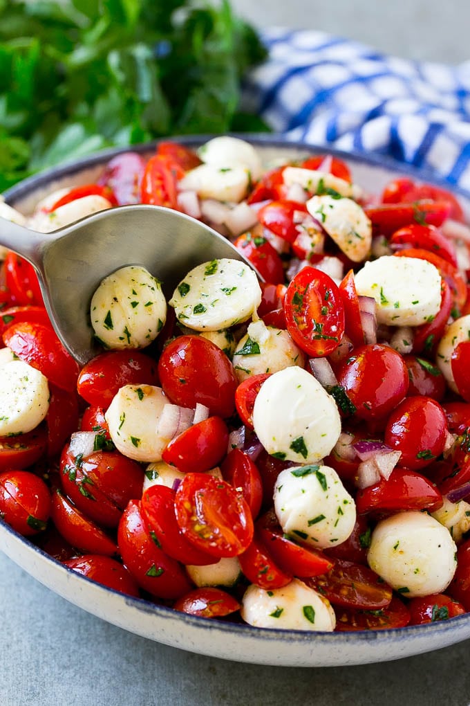 Un tazón de ensalada de tomate cherry con una cuchara para servir.