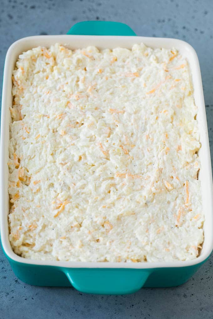 Una mezcla de patatas fritas, crema agria, queso y condimentos en una cacerola.