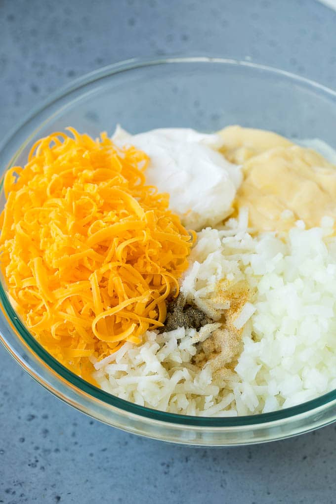 Un plato de patatas fritas, queso rallado, crema de pollo, crema agria y condimentos.