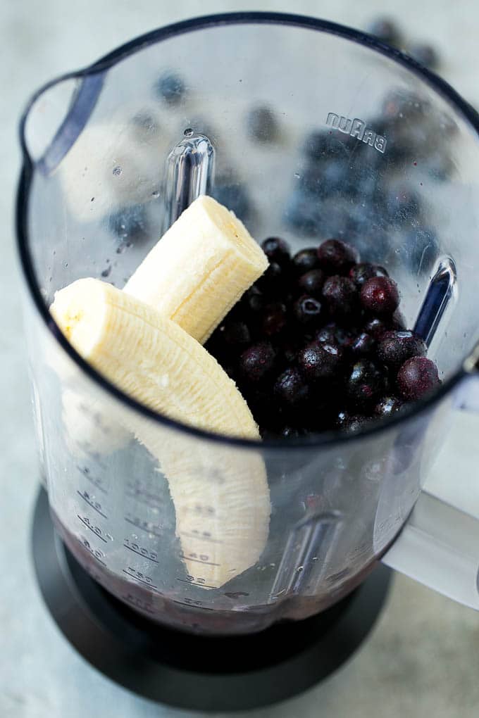 Arándanos, plátano, jugo de frutas y yogur en una licuadora.