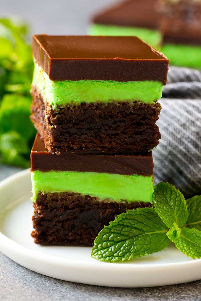 Receta de brownie de menta | Brownies en capas | Brownies helados #brownies #chocolate #frosting #mint #postre #dinneratthezoo Una pila de brownies de menta cubiertos con glaseado de chocolate con menta.