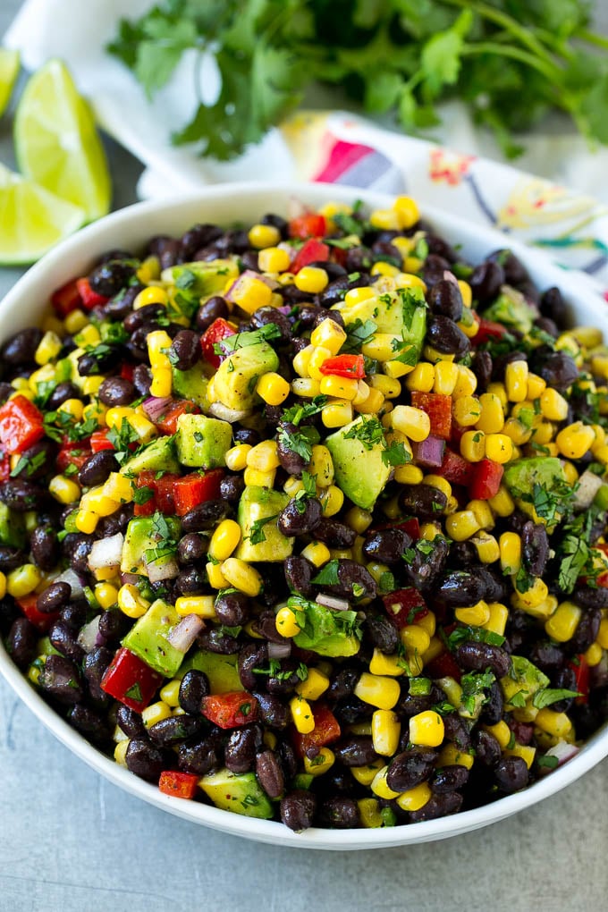 Un tazón de ensalada de frijoles negros con maíz, pimientos y aguacate.