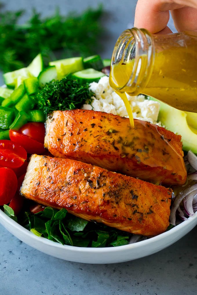 Filetes de salmón sobre las verduras con el aderezo vertido.