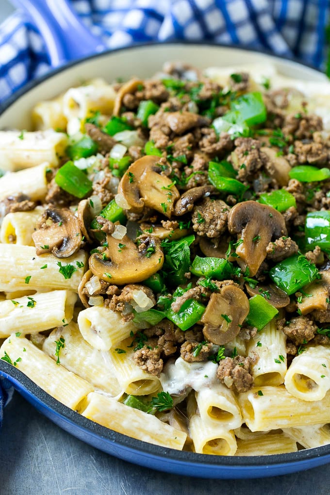 Una sartén de Philly Cheesesteak con rigatoni cremoso, carne molida, champiñones salteados y pimientos verdes.
