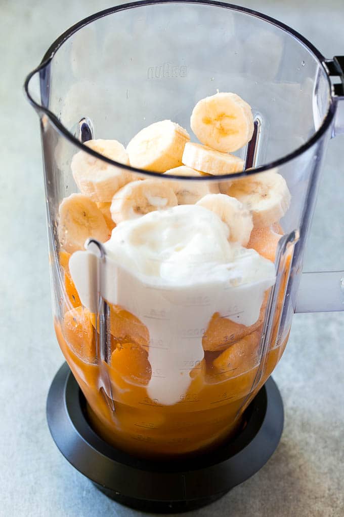 Néctar de durazno, duraznos congelados, mango, plátano y yogur en una licuadora.