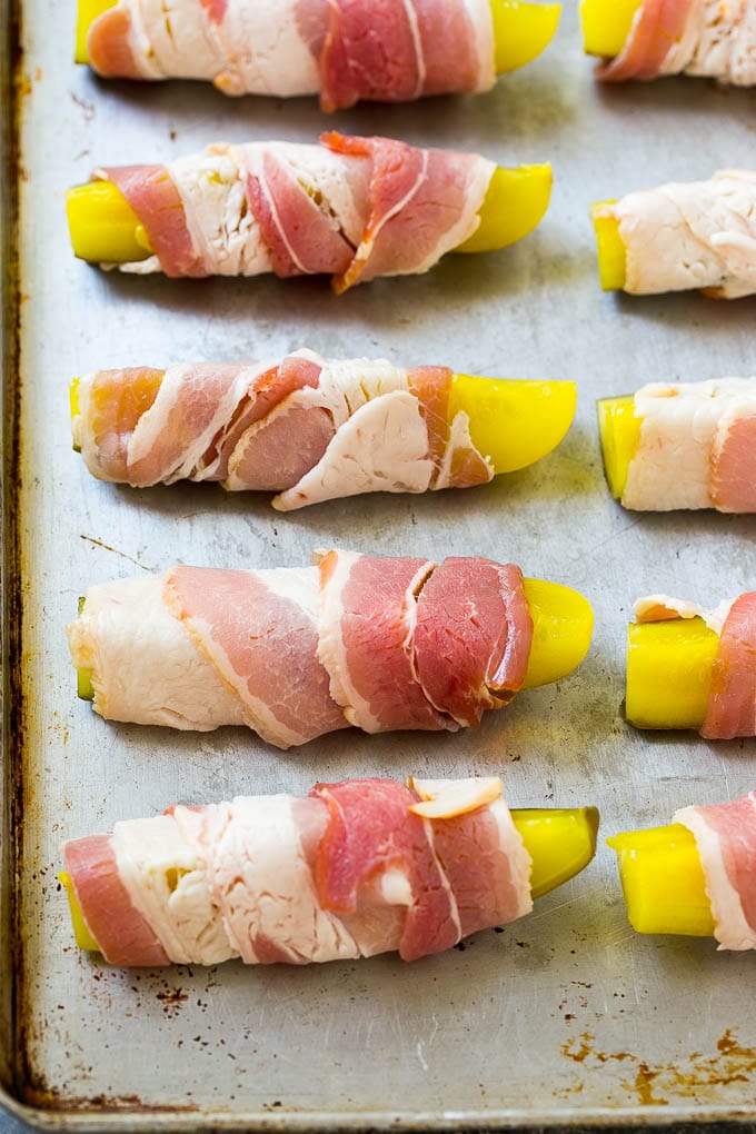 Receta de tocino envuelto en escabeche |  Patatas fritas encurtidas |  Receta baja en carbohidratos # encurtidos # tocino #lowcarb #keto #dinneratthezoo Lanzas en escabeche envueltas en tocino en una bandeja para hornear.