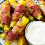 Encurtidos envueltos en tocino en un plato con una guarnición de aderezo ranch.
