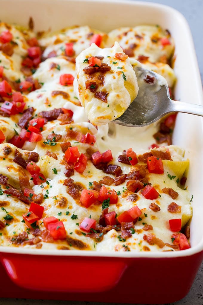 Una cazuela rellena de Pollo Alfredo con una cuchara para servir.