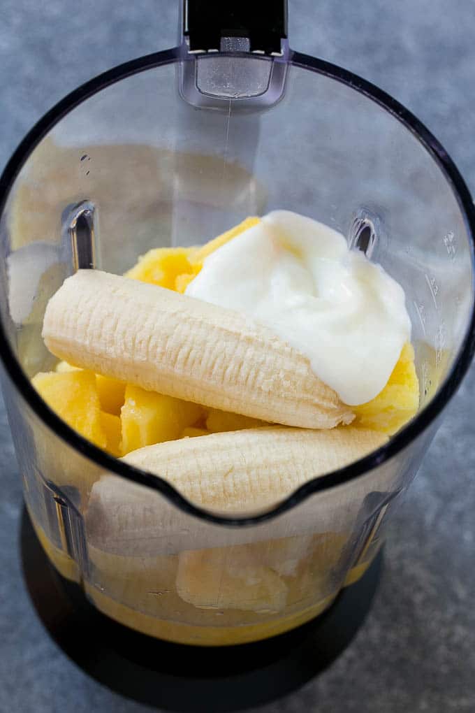 Piña congelada, jugo de piña, plátano y yogur en una licuadora.