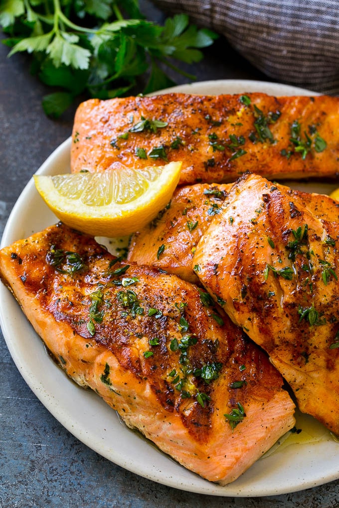 Un plato de filetes de salmón marinado a la parrilla aderezado con hierbas frescas.
