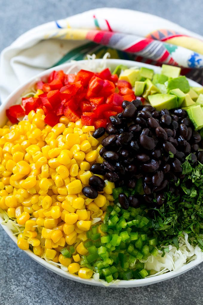 Un tazón de col rizada picada, maíz, frijoles negros, pimientos rojos, jalapeño y aguacate.