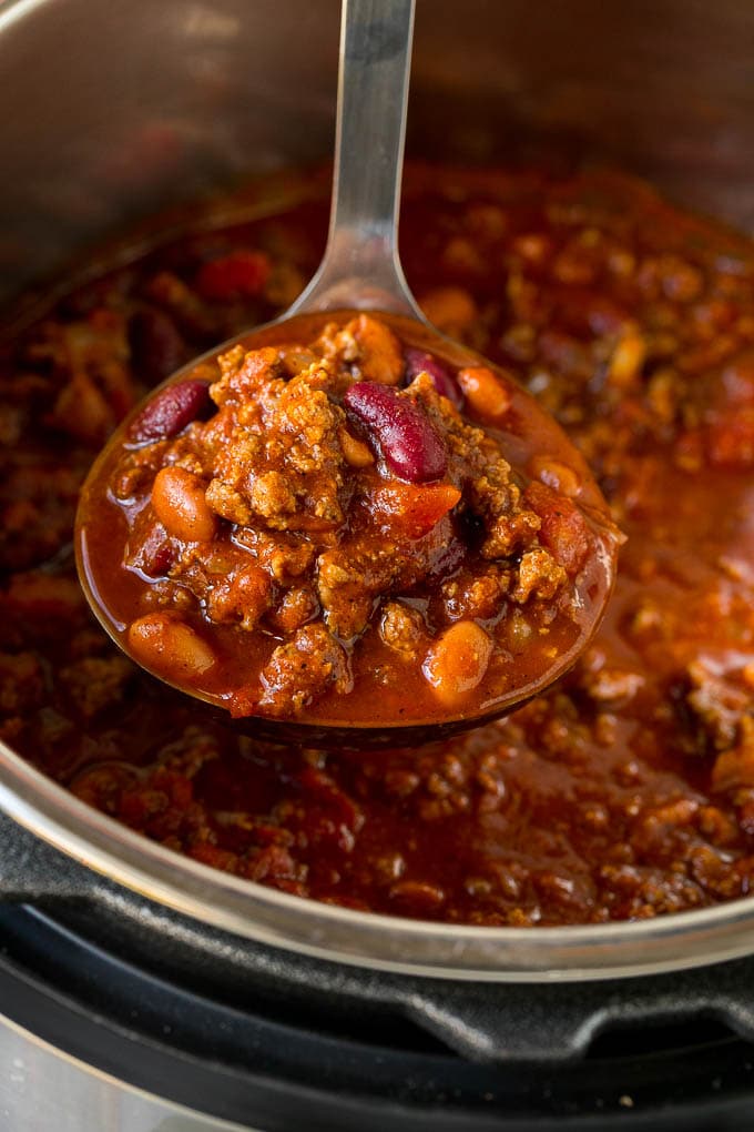 Un cucharón lleno de chile Instant Pot con carne y frijoles.