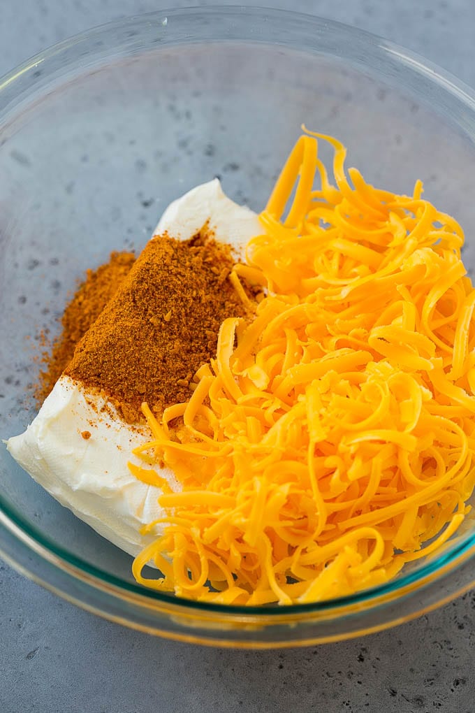 Queso crema, queso cheddar y condimento para tacos en un bol.