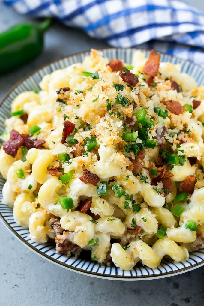 Un tazón de macarrones con queso jalapeño cubierto con pan rallado crujiente, tocino y chiles jalapeños.