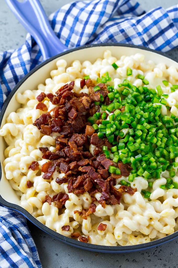 Macarrones con queso en una sartén cubierta con tocino y jalapeños cortados en cubitos.