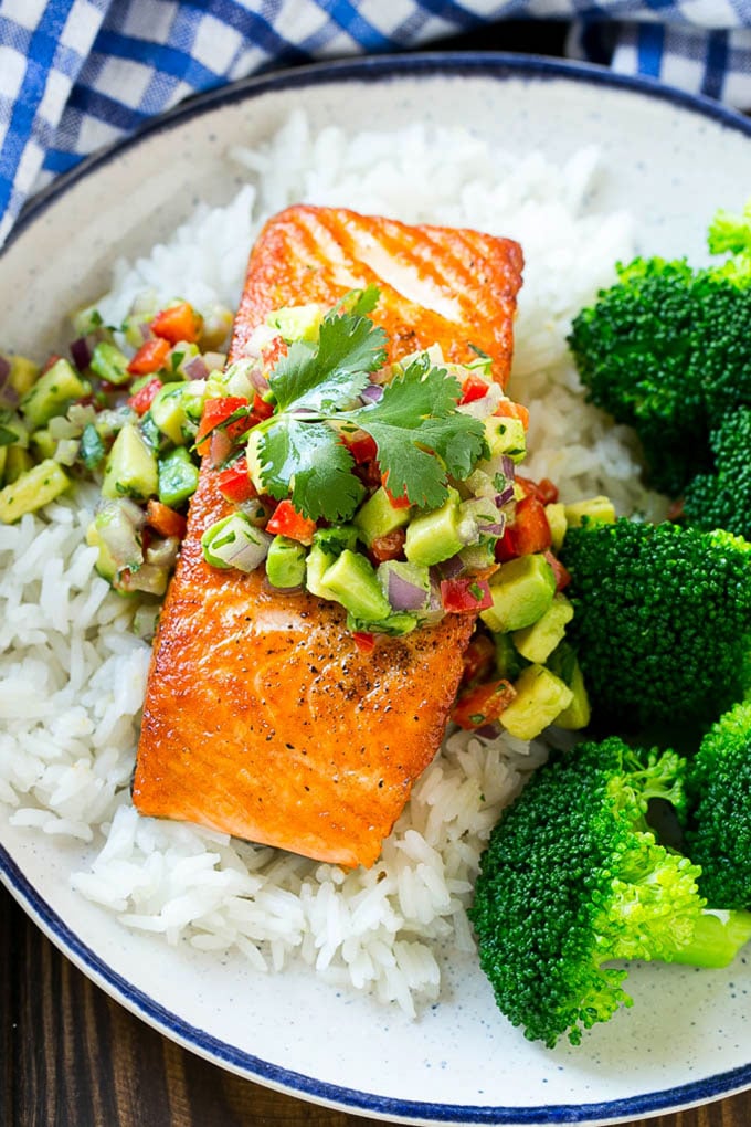 Filete de salmón con salsa de aguacate servido sobre arroz y brócoli.