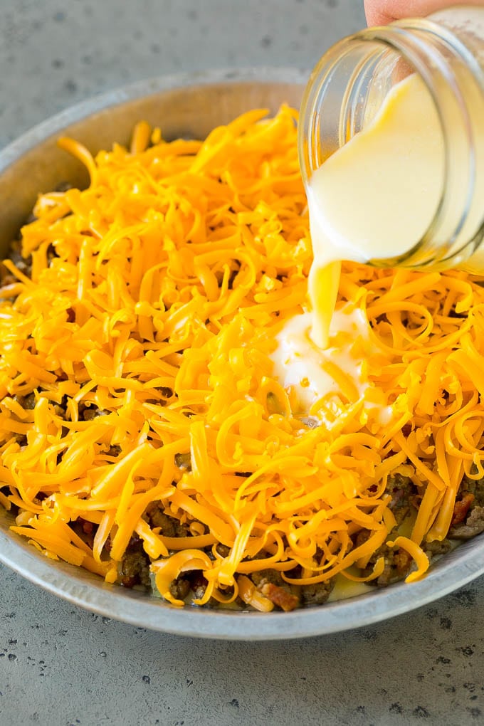 La masa de huevo se vierte sobre queso rallado y carne picada.