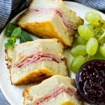 Un plato de sándwich Monte Cristo con fruta fresca y mermelada de frambuesa para mojar.