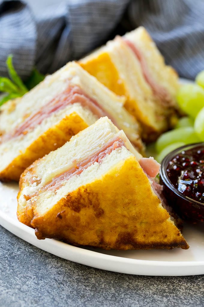 Gajos de sándwich Monte Cristo recubiertos con azúcar glass y servidos con mermelada de frambuesa.