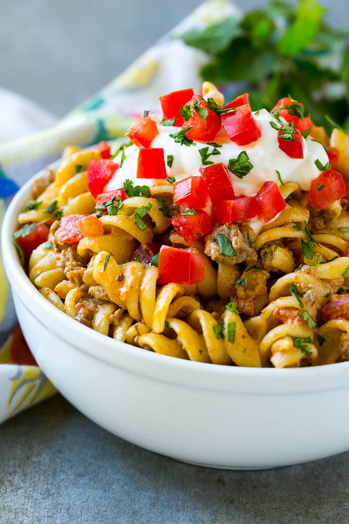 Un tazón de pasta para tacos cubierto con crema agria, tomates y cilantro.