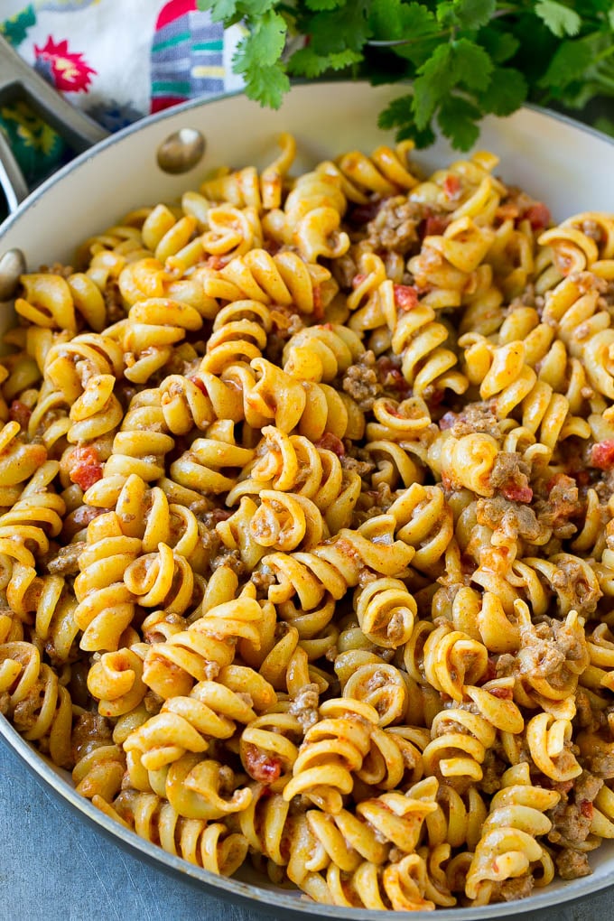 Rotini de pasta mezclado con carne picada y tomates en una salsa cremosa.