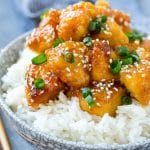 Pollo a la naranja en olla de cocción lenta servido en un tazón de arroz.