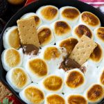 Una sartén de salsa s'mores de chocolate con leche derretida cubierta con malvaviscos tostados.