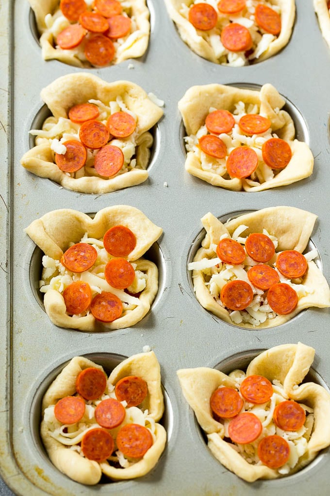 Tazones de pizza sin cocer rellenos de queso, salsa y pimientos.