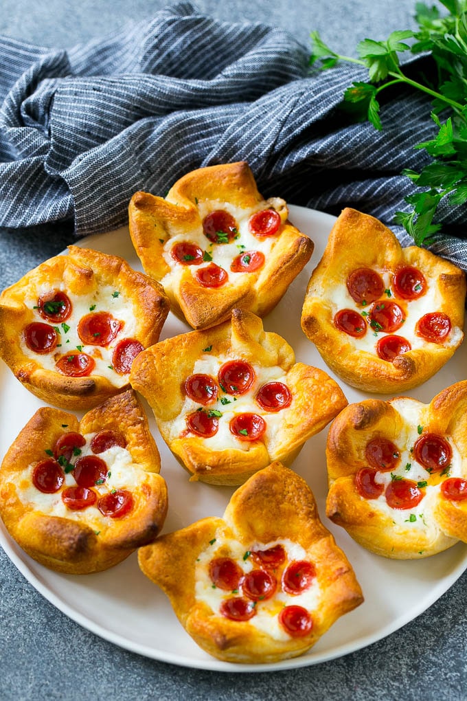 Muffins de pizza en un plato para servir aderezado con perejil.