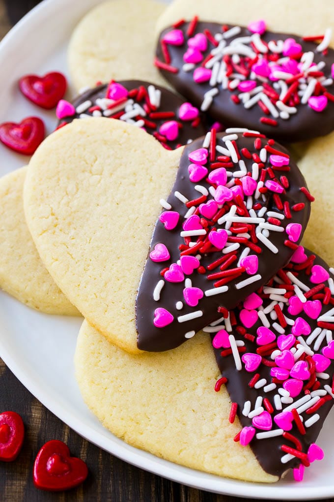 Receta de galletas de corazón | Galletas de azúcar de corazón | Galletas de San Valentín | Galletas de azúcar en forma de corazón | Postre de San Valentín #corazones #cookies #sugarcookies #valentinesday #sprinkles #dessert #dinneratthezoo Galletas de azúcar en forma de corazón medio sumergidas en chocolate negro y cubiertas con chispitas de San Valentín.