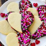 Galletas en forma de corazón bañadas en chocolate amargo y decoradas con hojuelas de San Valentín.