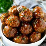 Un tazón de albóndigas agridulces con un tenedor de cóctel.