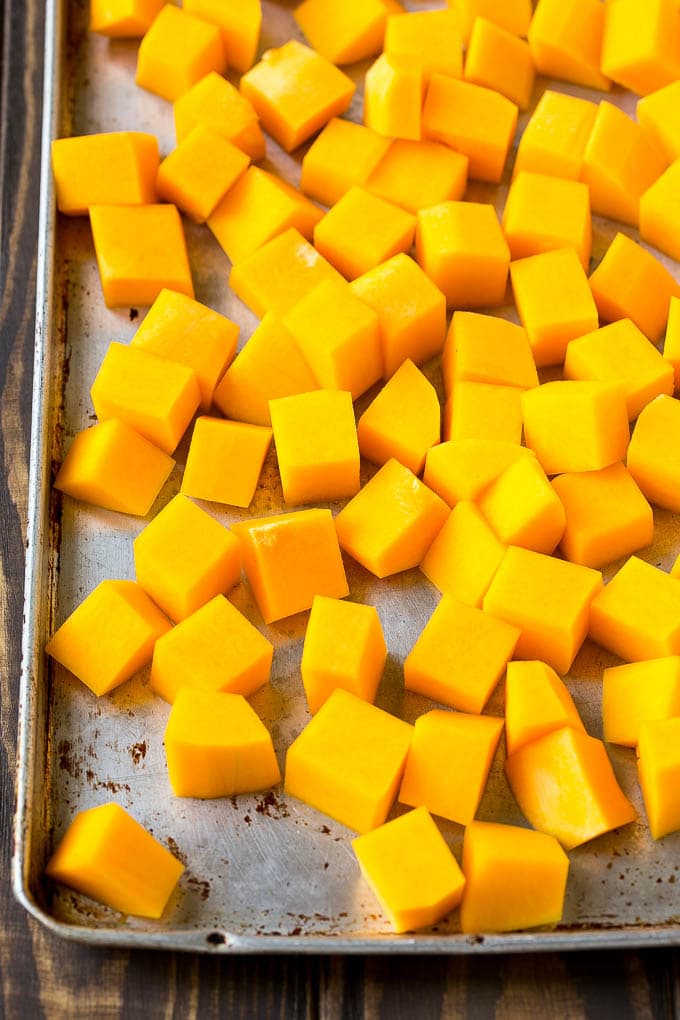 Calabaza moscada cruda cortada en cubos en una bandeja para hornear.