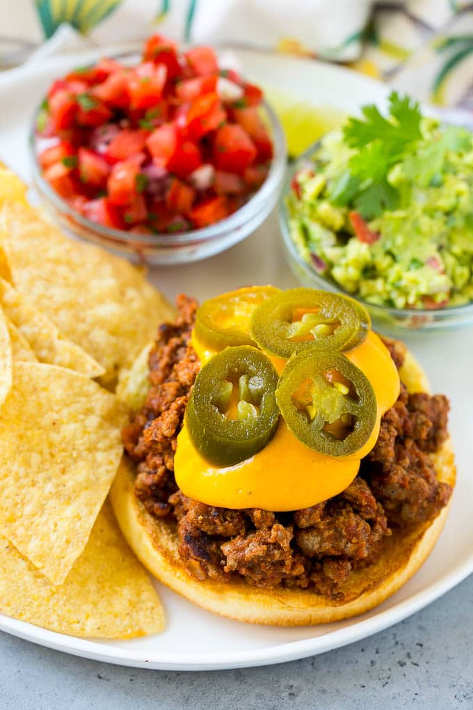 Un pan de hamburguesa con carne descuidada de Joe, salsa de queso nacho y chiles jalapeños.