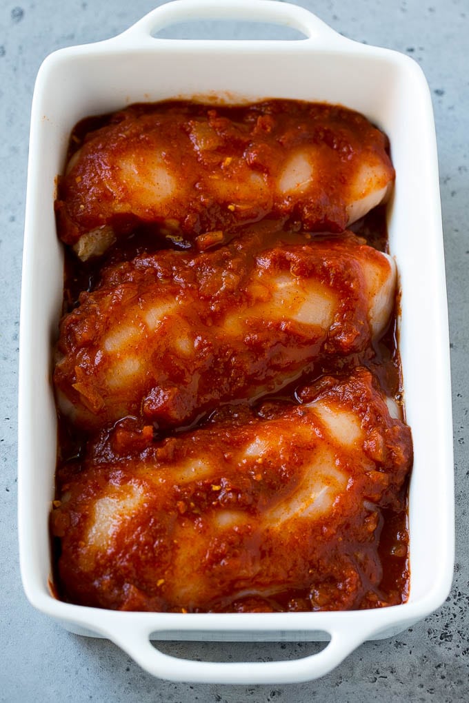 Pechugas de pollo en una sartén cubiertas con salsa.