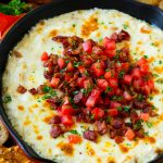 Pollo Alfredo cocinado en una sartén con tocino, tomates y perejil picado.