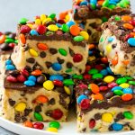 Un plato de barras de masa para galletas espolvoreadas con chispas de chocolate y M & M's.