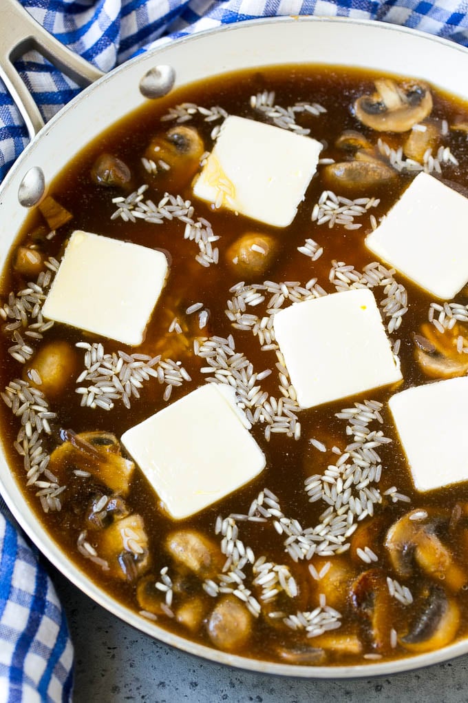 Arroz con caldo de res, sopa de cebolla y mantequilla en una sartén.