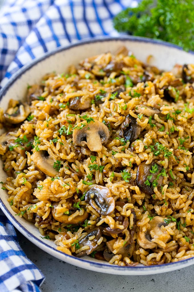 Un tazón de arroz con champiñones al horno aderezado con perejil picado.