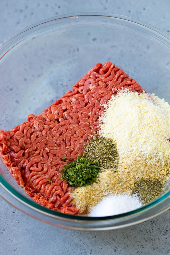 Carne picada, pan rallado, perejil, hierbas y parmesano en un bol.