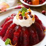 La gelatina de frambuesa se combina con salsa de arándanos, piña y ralladura de naranja para una deliciosa guarnición o un postre perfecto para las fiestas.