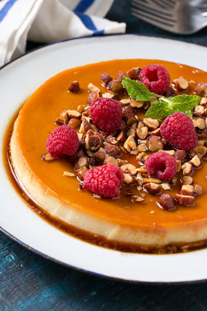 Este rico y cremoso flan está aromatizado con vainilla y almendras y se completa con almendras tostadas picadas y frambuesas.
