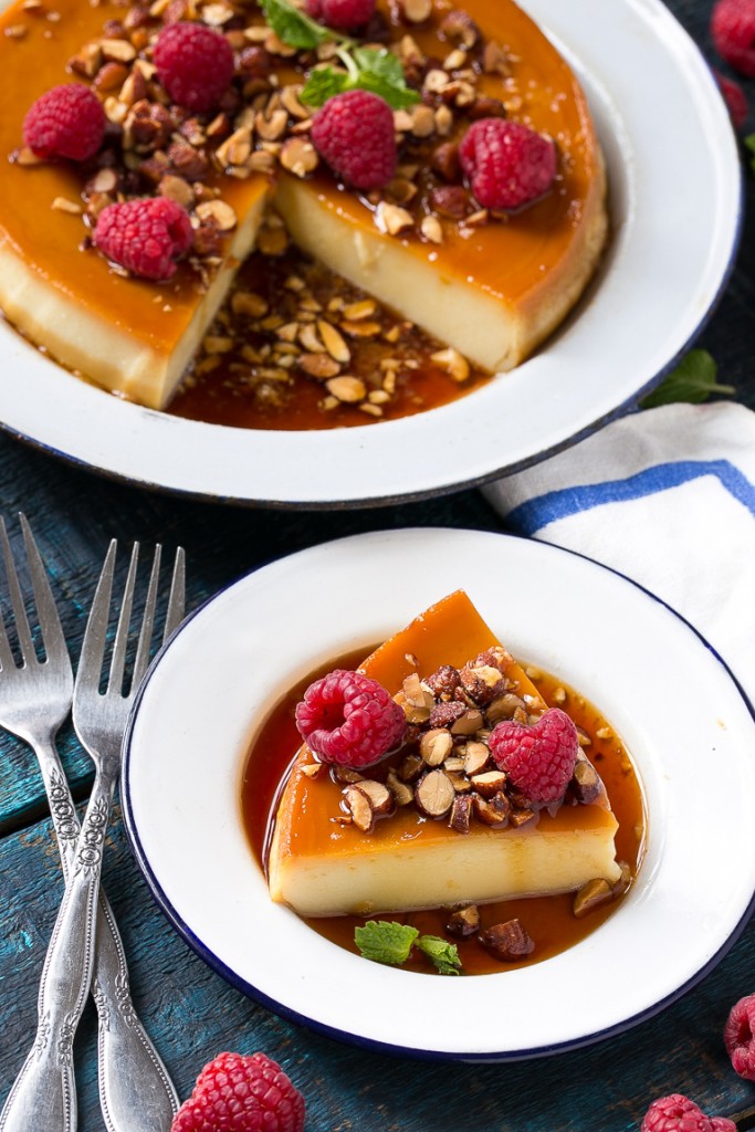 Este flan rico y cremoso está aromatizado con vainilla y almendras y se completa con almendras tostadas y frambuesas picadas.