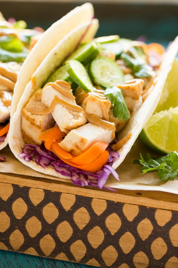 Estos tacos de pollo tailandeses son una cena rápida y fácil.  El pollo marinado con coco se rellena en tortillas calientes con verduras frescas y una generosa cantidad de salsa de maní casera.
