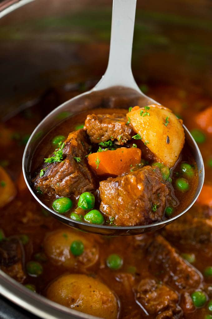 Receta de estofado de carne instantánea | Estofado de ternera en olla a presión | Estofado de ternera #beef #stew #soup #pressurecooker #instantpot #dinner #dinneratthezoo Cucharón relleno de estofado de ternera instantáneo con trozos de ternera, zanahorias, patatas y guisantes.
