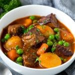 Un plato de estofado de ternera instantáneo con carne picada, patatas, zanahorias, cebollas y guisantes.